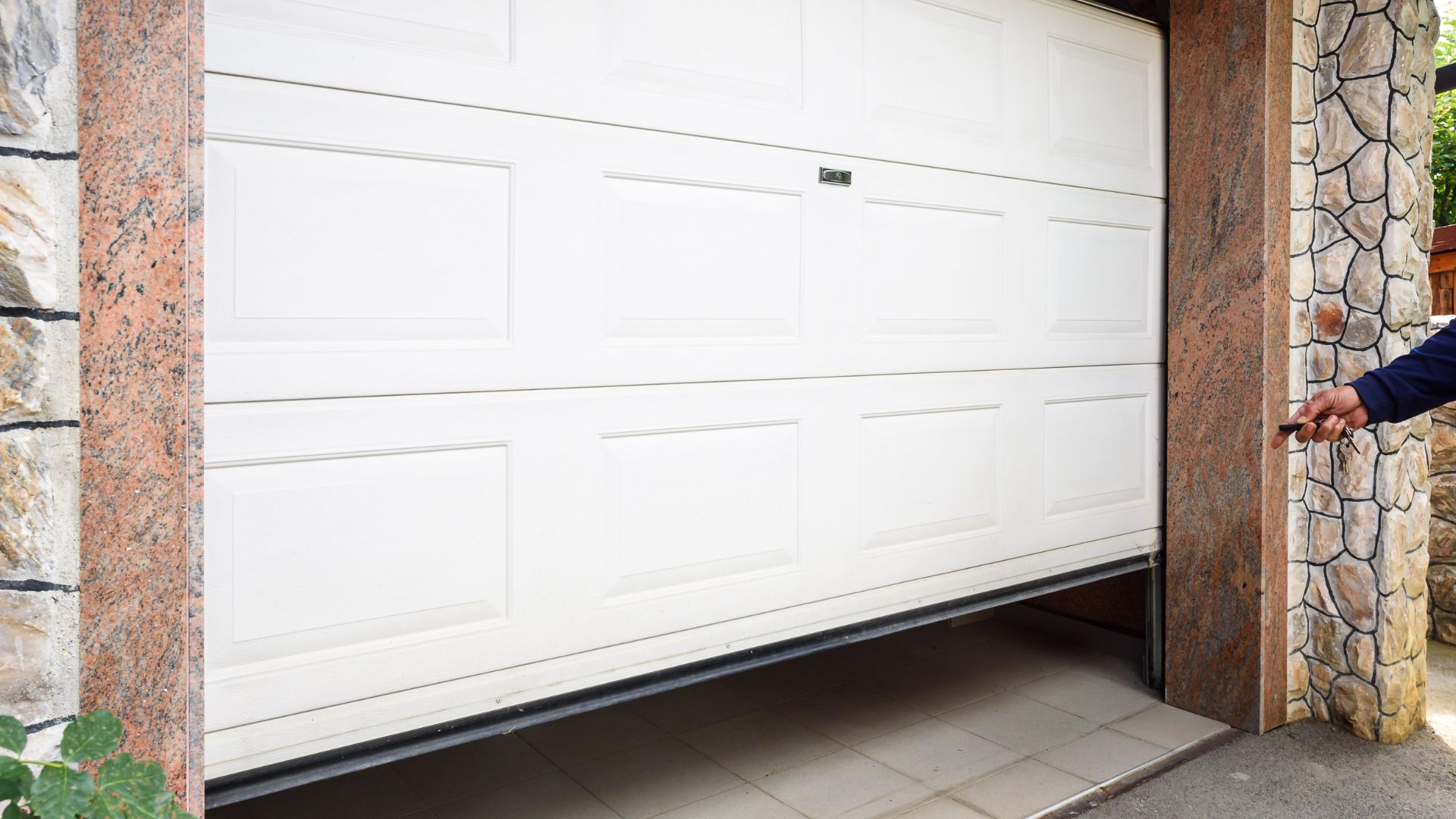 White garage door partially open with stone and marble columns