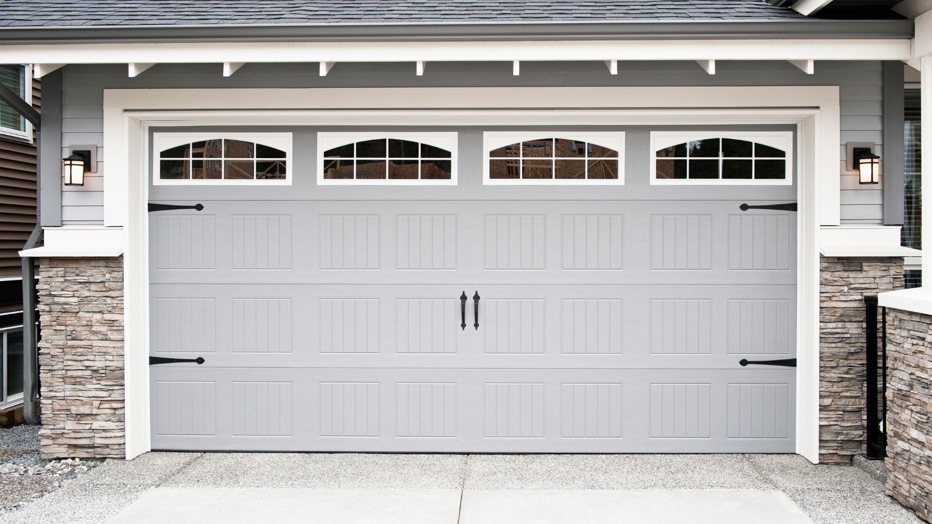White two-car garage with arched windows and stone facade accents