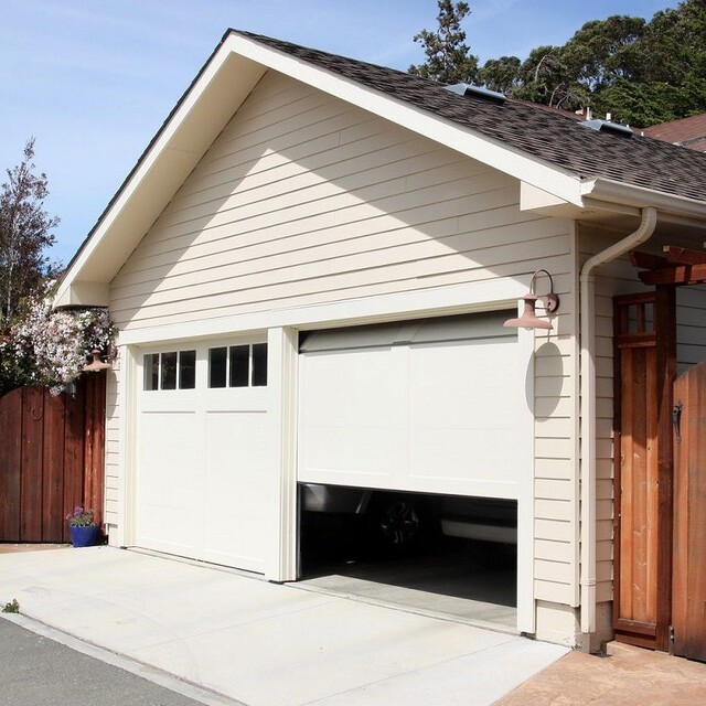 A white garage with a brown door and a brown fence