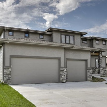 A two story house with two garages and a driveway