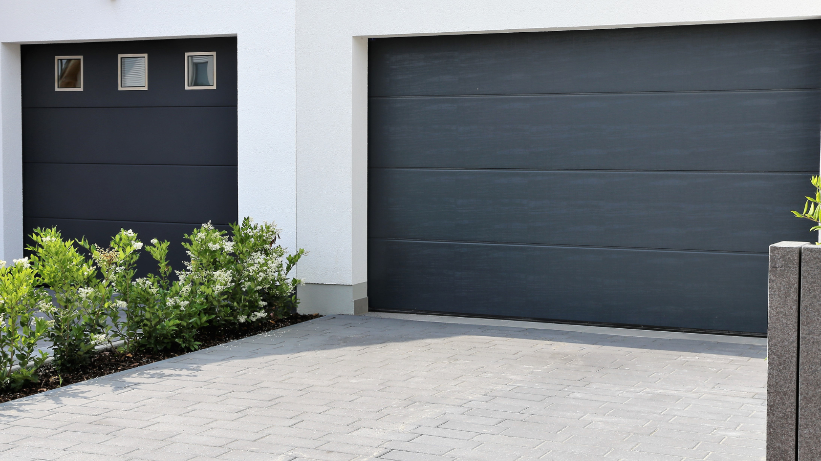 A black garage door next to a white house