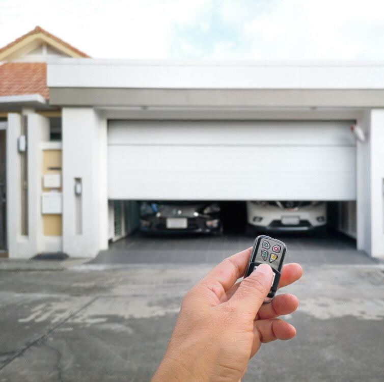 A hand holding a cell phone in front of a garage